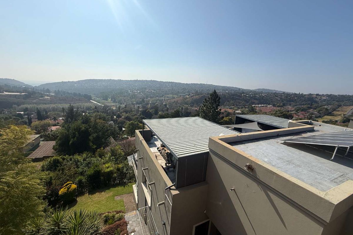An elevated aerial view of the property showing the roof structure, solar panel installation, and expansive surrounding landscape views.
