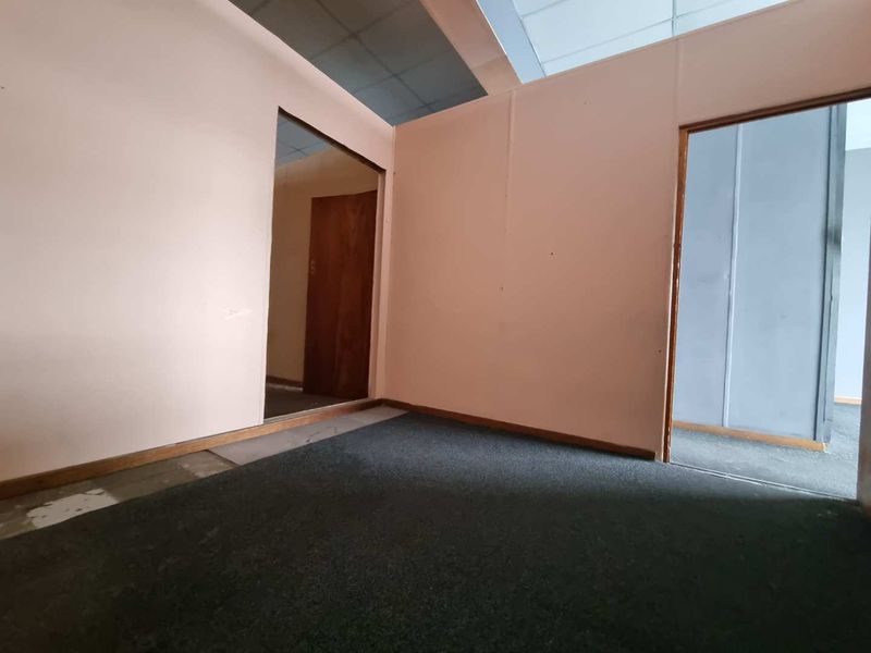 An empty office space featuring partition walls, carpet flooring, and multiple doorways, requiring cosmetic updates to improve its professional appeal.