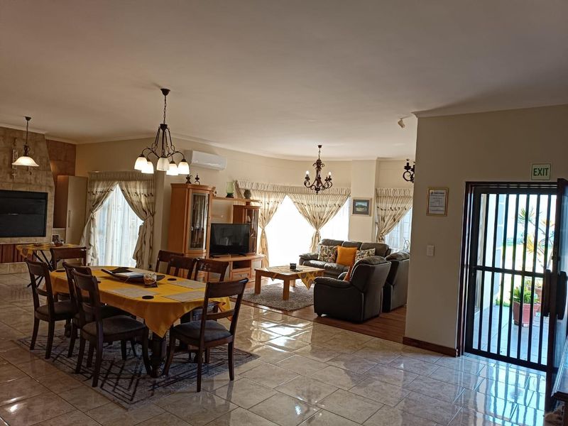 Spacious open-plan living and dining area featuring tiled flooring, a built-in fireplace, and split-system air conditioning, with direct access to the exterior.