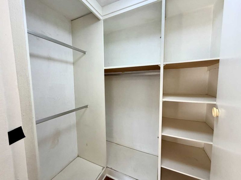 A walk-in closet featuring built-in shelving and hanging rails, providing ample storage space within the bedroom.