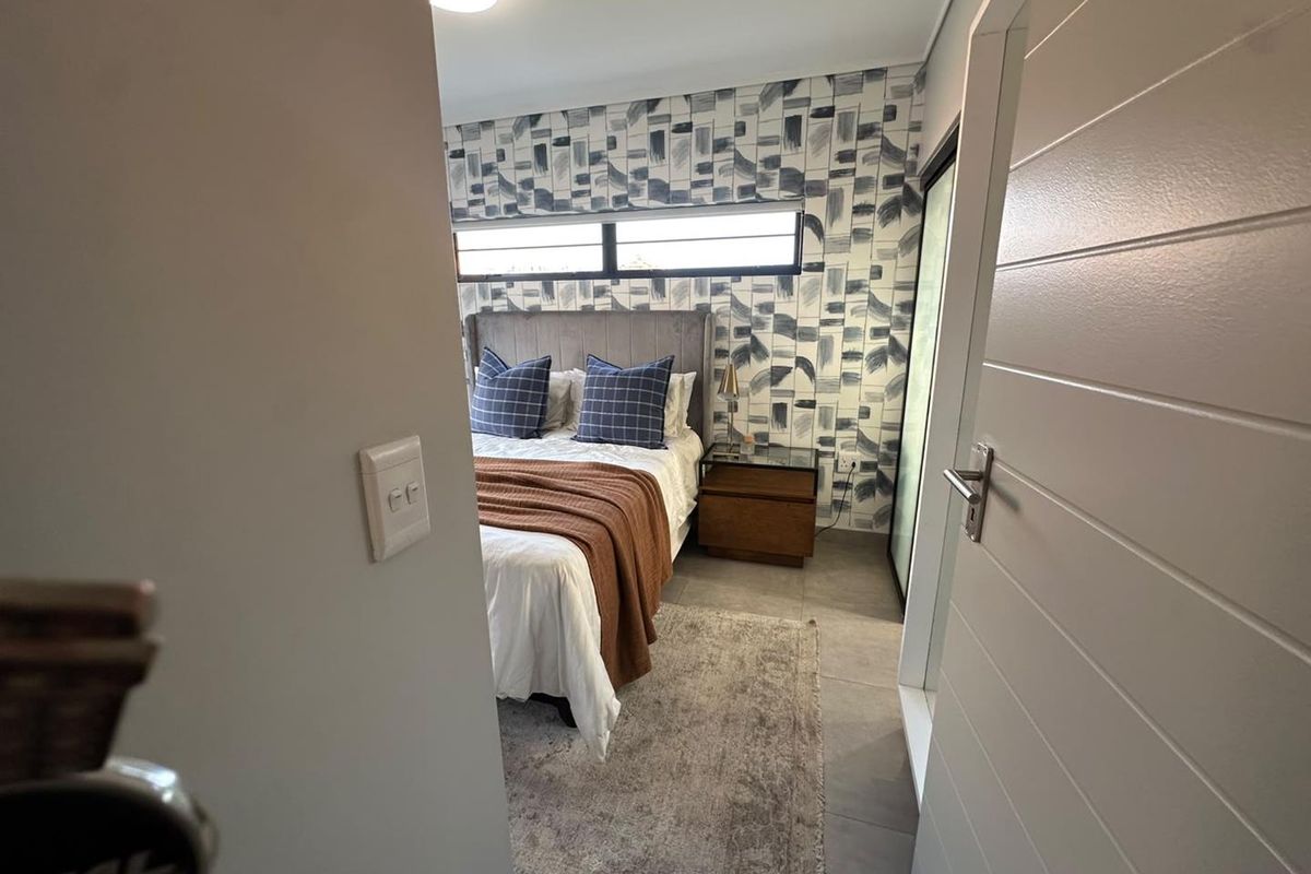 A well-maintained bedroom featuring tiled flooring, a horizontal clerestory window, and a modern accent wall, viewed from the doorway.