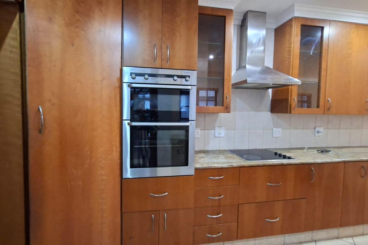 A functional kitchen featuring wooden cabinetry, granite countertops, a built-in double oven, and a stainless steel extractor fan.