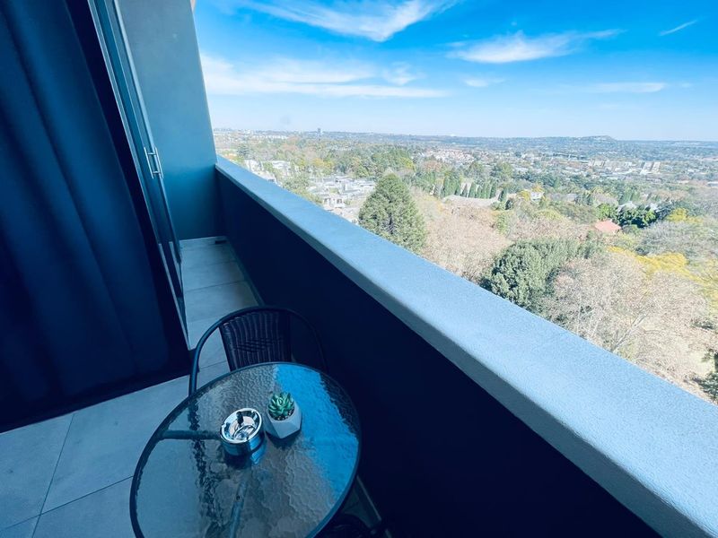 A private balcony featuring tiled flooring and a solid balustrade, offering expansive elevated views of the surrounding landscape.
