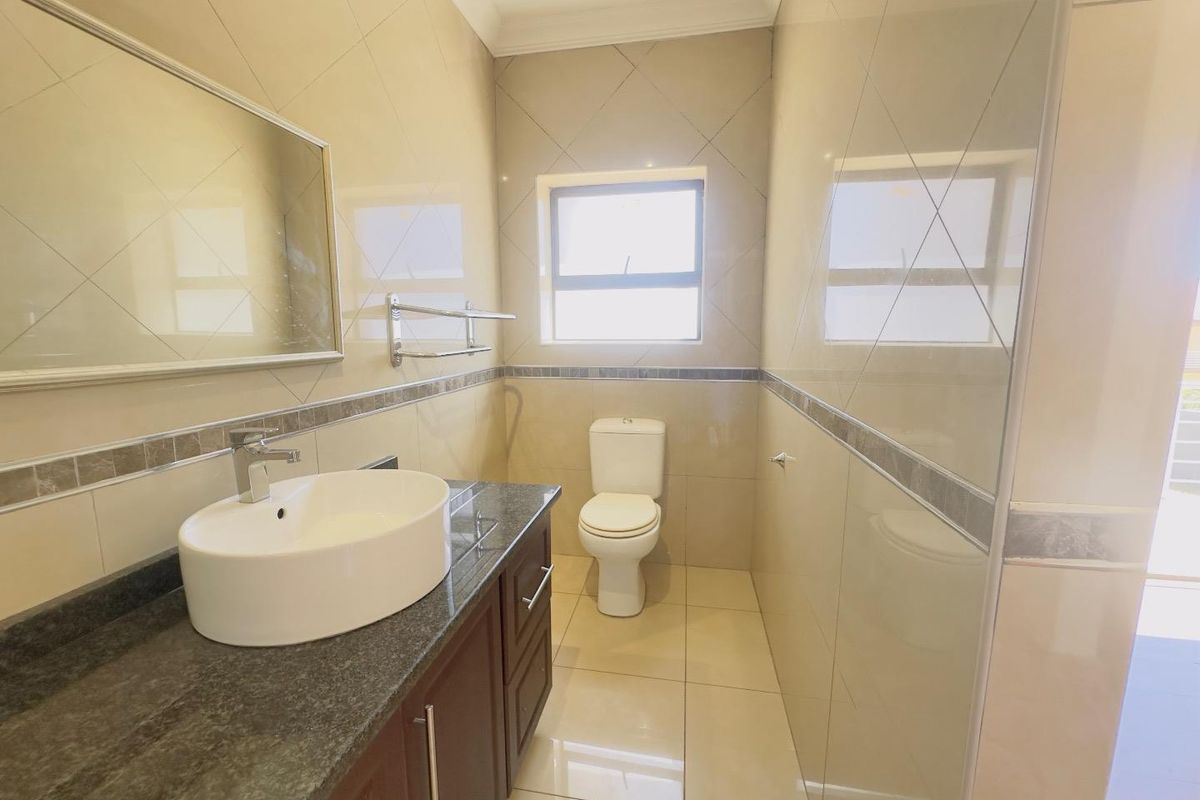 A clean, modern bathroom featuring a vessel sink vanity with granite countertop, tiled walls, and a standard toilet.