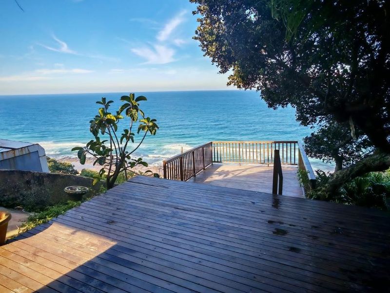 An elevated timber deck offering expansive ocean views, featuring a wooden balustrade and direct access to the coastal scenery.