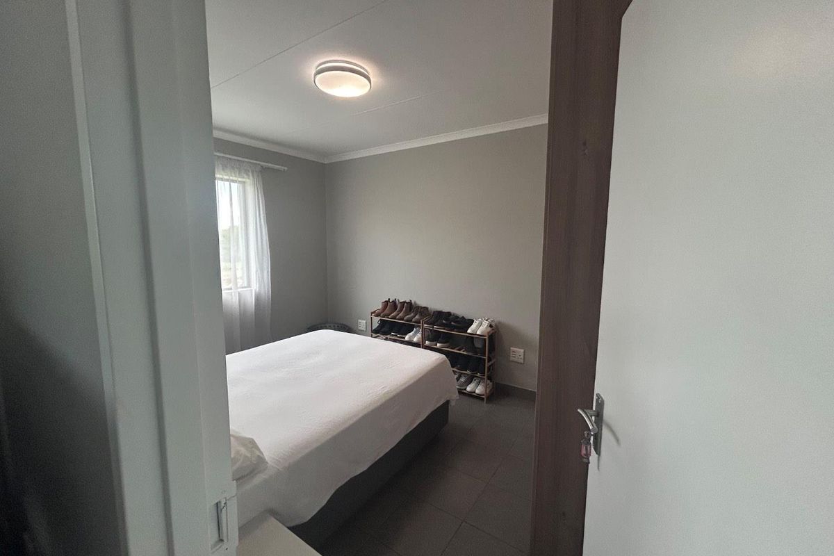 A functional bedroom featuring tiled flooring, neutral wall tones, and a central ceiling light fixture, viewed from the doorway.