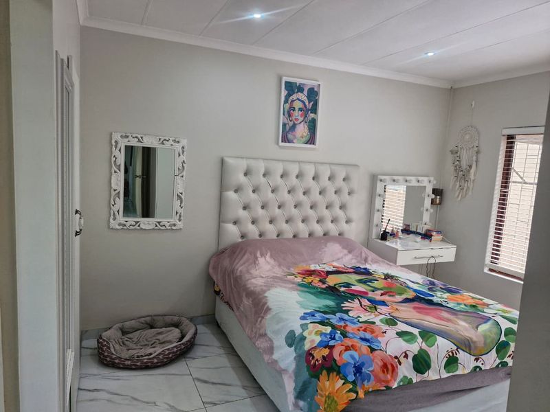 A well-maintained bedroom featuring tiled flooring, recessed downlighting, and venetian blinds, offering a clean and functional living space.