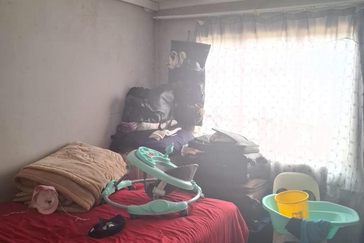 A bedroom featuring a window with natural light, requiring cosmetic updates and repairs to the walls and ceiling.