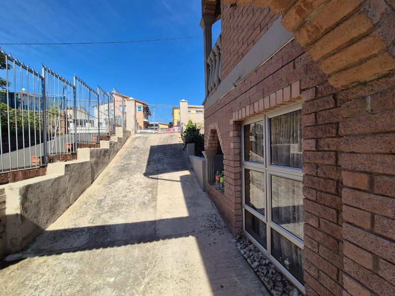 Exterior view of the property featuring a brick facade, concrete driveway, and metal perimeter fencing.