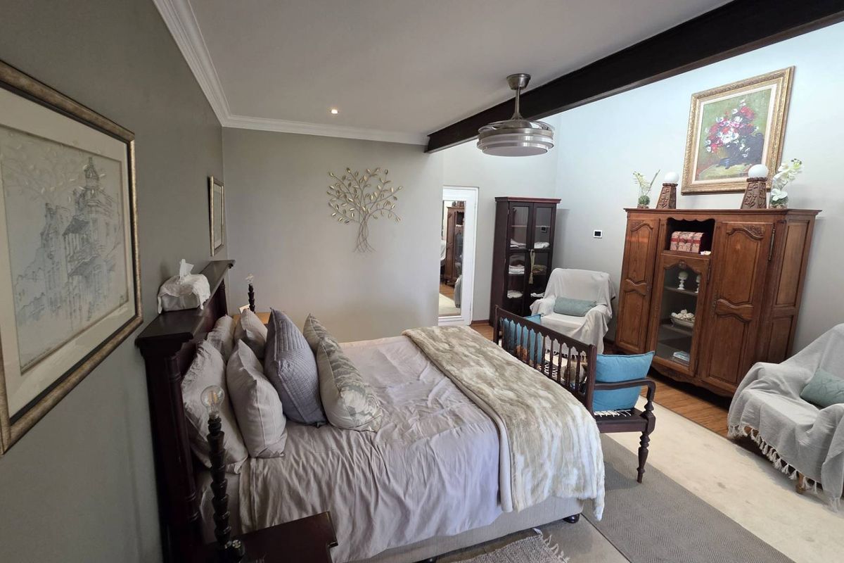 Spacious bedroom featuring a high ceiling with an exposed beam, ceiling fan, and neutral wall finishes.