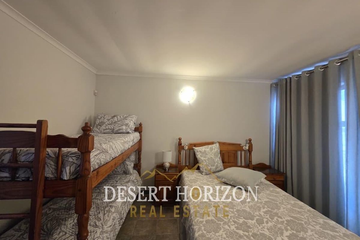 A bedroom featuring tiled flooring and neutral wall finishes, currently configured with multiple beds.