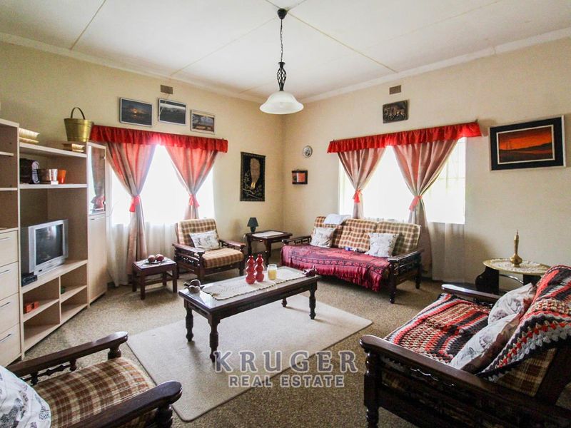 A traditional living room featuring carpeted flooring and a central pendant light fixture, offering a comfortable and functional space for relaxation.