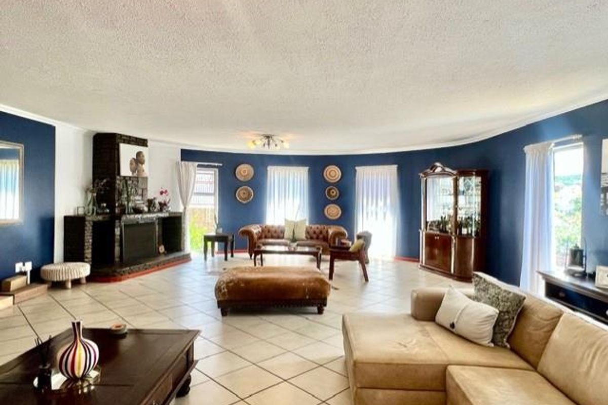 Spacious living room featuring a curved wall design, a built-in fireplace with stone cladding, and large windows allowing for ample natural light.