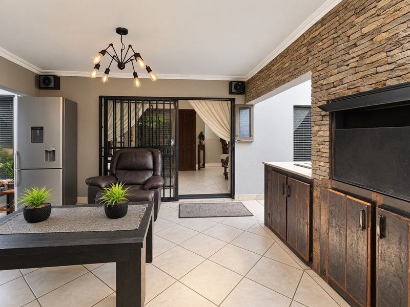 Covered patio area featuring a built-in braai, stone cladding feature wall, tiled flooring, and built-in cabinetry with stone countertops.