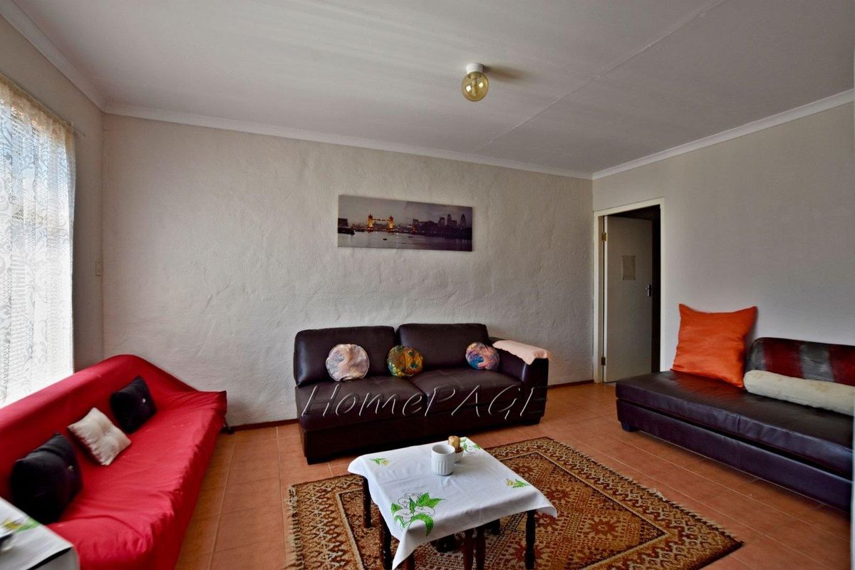 A living room featuring tiled flooring and textured walls, providing a functional space for relaxation.