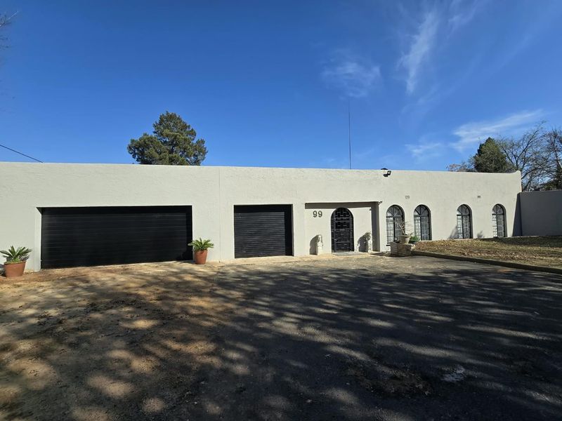 Front elevation of a single-story residence featuring a double garage, arched windows, and a paved driveway entrance.