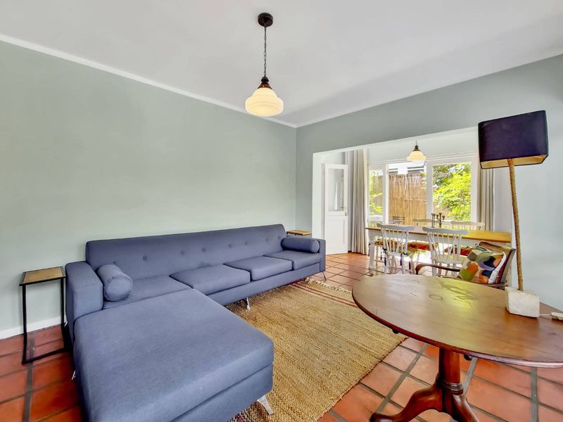 Spacious open-plan living and dining area featuring terracotta floor tiles, neutral walls, and direct access to an outdoor patio through glass sliding doors.