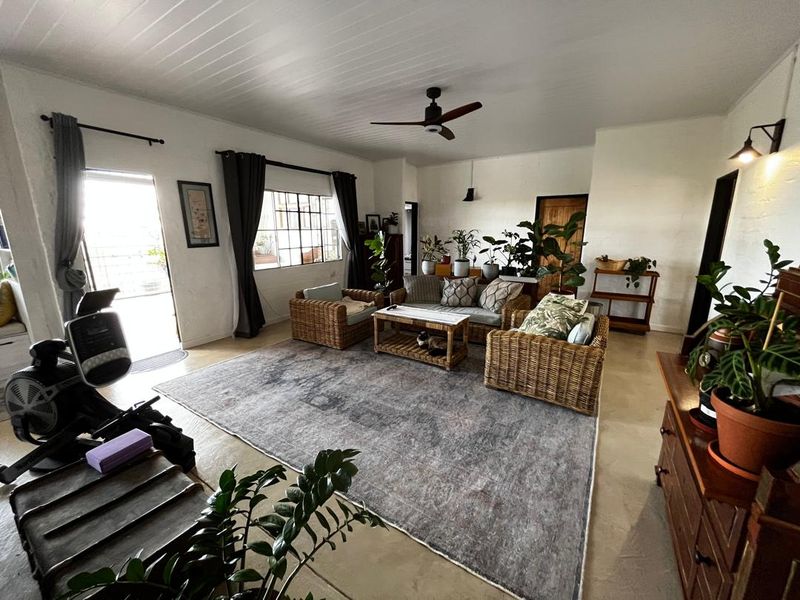 Spacious living room featuring concrete flooring, a tongue and groove ceiling, and large steel-framed windows providing natural light.