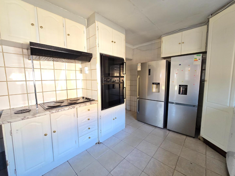 A functional kitchen featuring built-in cabinetry, a ceramic tile backsplash, and integrated cooking appliances including an oven and hob.