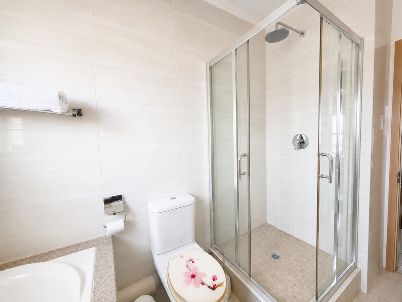 Modern bathroom featuring a glass-enclosed shower, neutral wall tiling, and standard sanitary fixtures.
