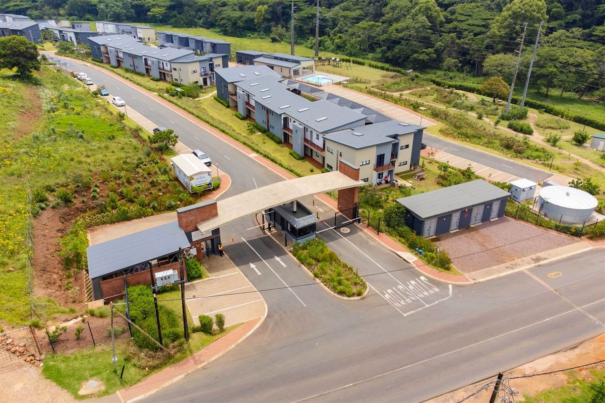 Aerial view of a secure residential apartment complex featuring a gated entrance, paved access roads, and landscaped grounds.