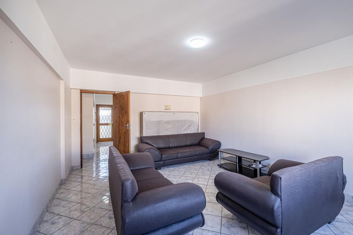 A spacious living room featuring neutral walls and tiled flooring, providing a functional and open area for relaxation.