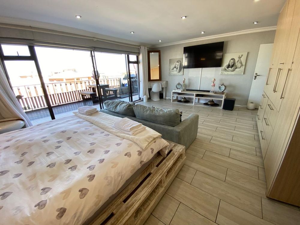 First-floor main bedroom with built-in cupboards and en-suite bathroom. It also has a balcony with distant sea views