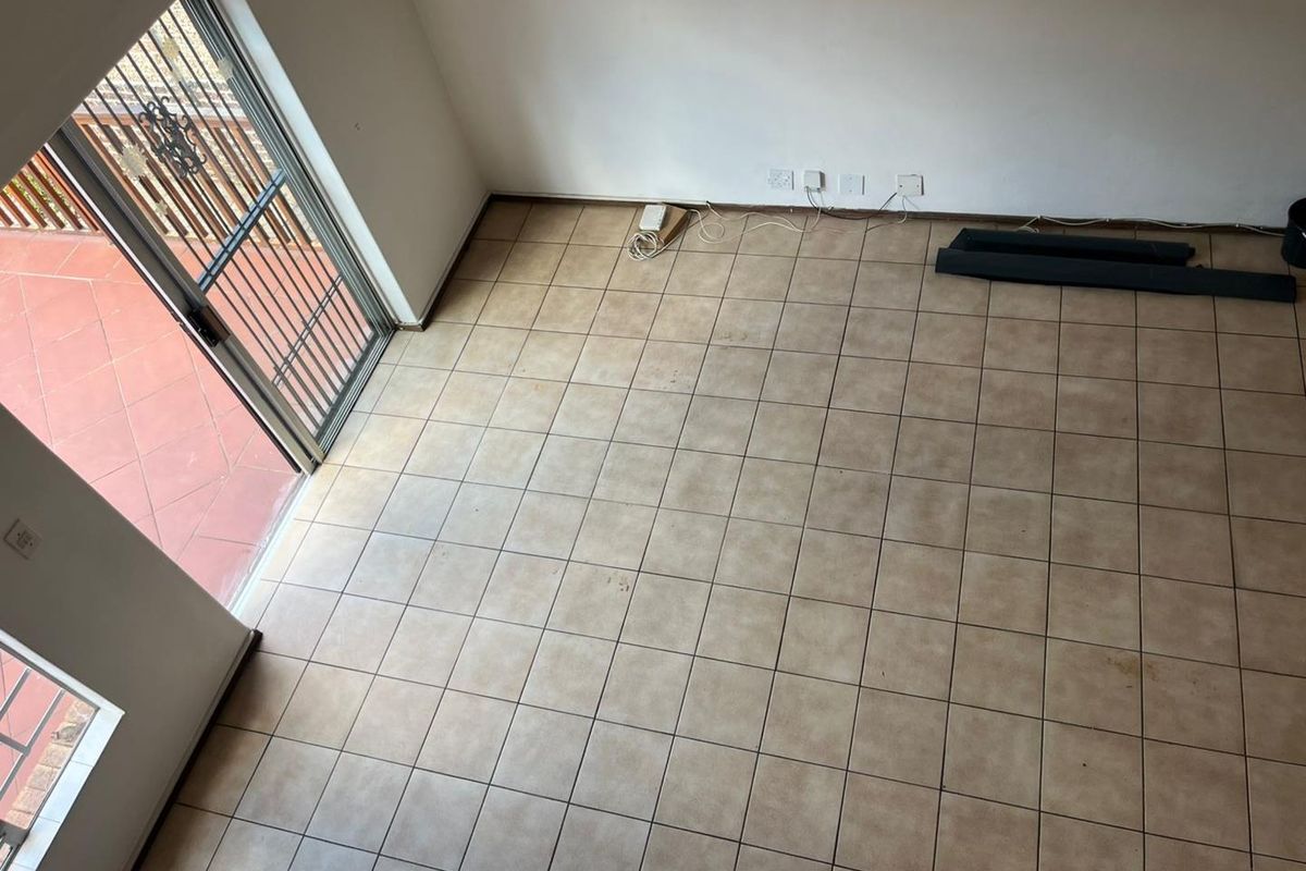 An empty living area featuring tiled flooring and a sliding glass door providing access to an outdoor patio space.