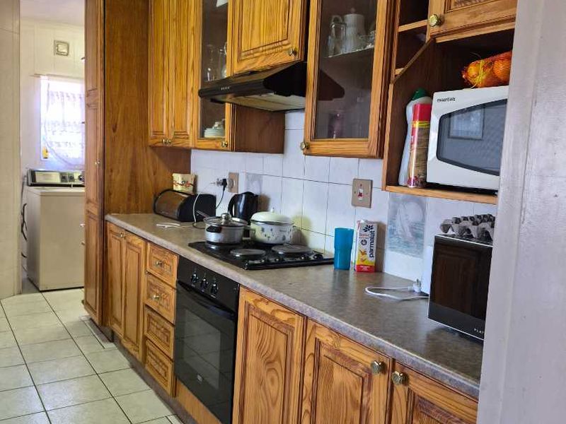 A functional kitchen featuring traditional wooden cabinetry, laminate countertops, a built-in oven with gas hob, and tiled flooring, offering a classic aesthetic.
