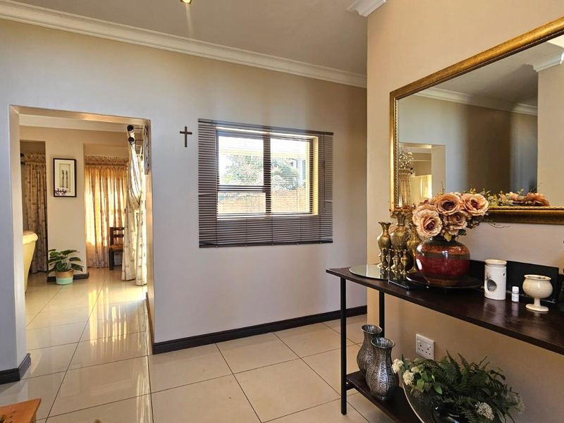 A bright and welcoming entrance hall featuring neutral wall tones, polished tiled flooring, and a clear view through to the adjoining living space.