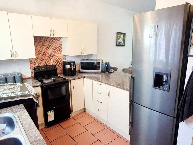 Functional kitchen featuring light-toned cabinetry, granite countertops, mosaic tile backsplash, and ceramic floor tiles, providing a practical workspace.