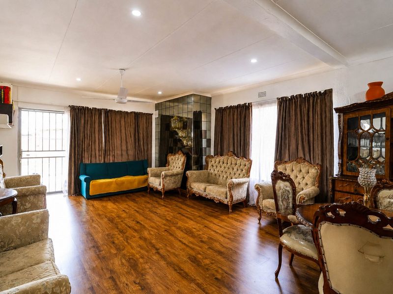 Spacious living area featuring warm laminate flooring, a decorative mirrored wall feature, and recessed lighting, providing a comfortable and functional space.