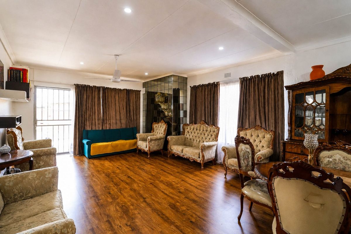 Spacious living area featuring warm laminate flooring, a decorative mirrored wall feature, and recessed lighting, providing a comfortable and functional space.
