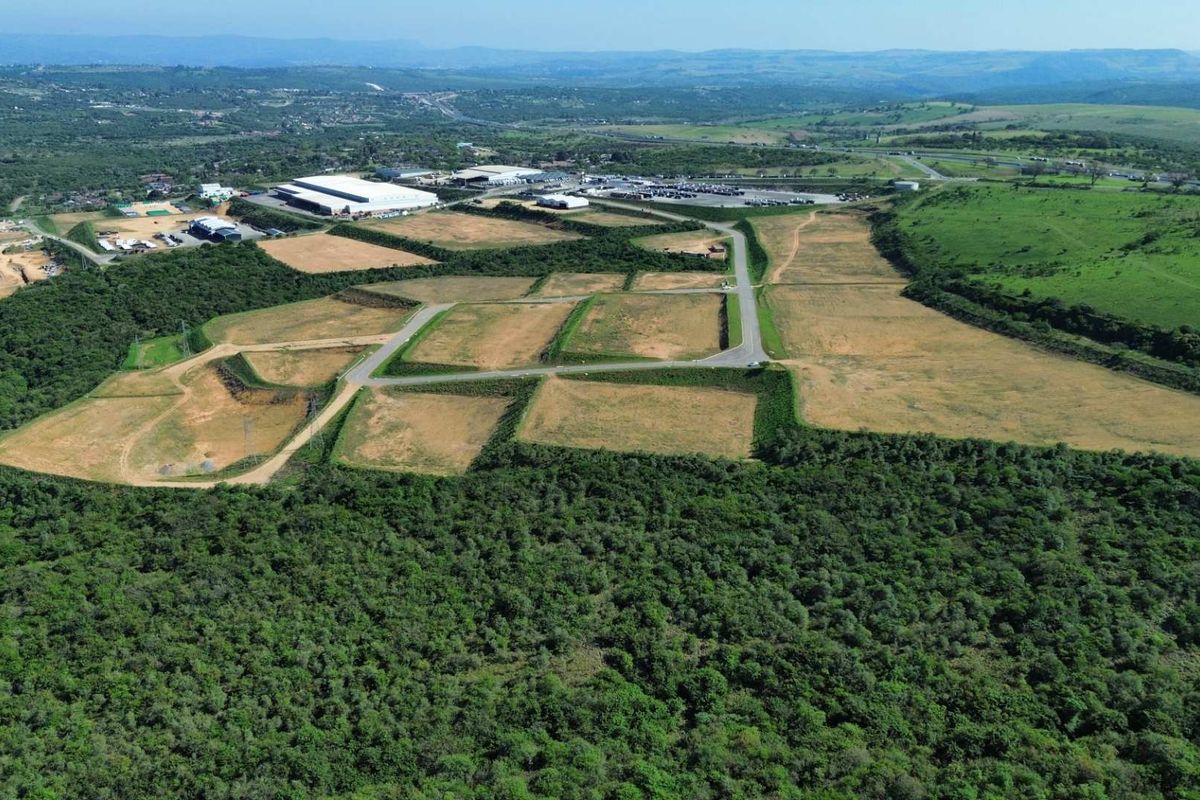 Aerial view of a large industrial development site featuring cleared land plots, paved access roads, and surrounding natural landscape.