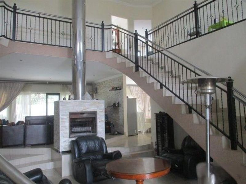 Spacious living area featuring a prominent central fireplace with stainless steel flue and an elegant staircase with wrought iron railings.