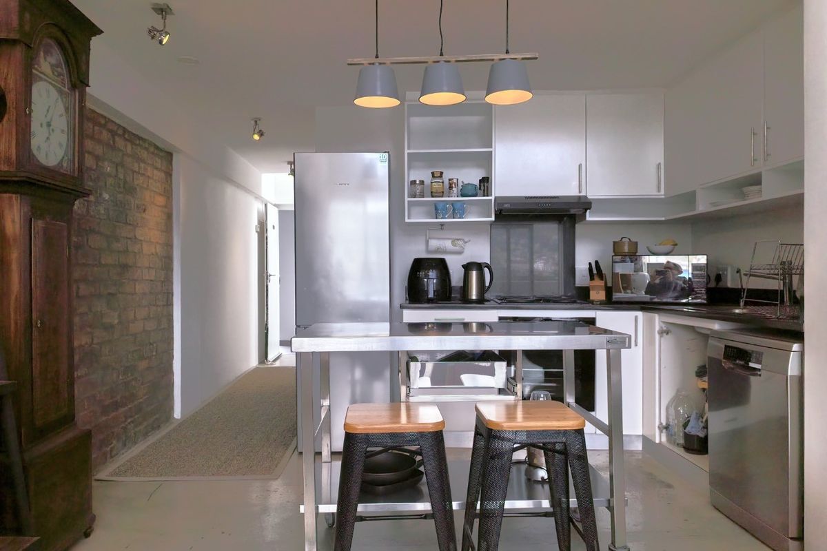Modern kitchen featuring white cabinetry, stainless steel appliances, and a striking exposed brick wall, creating a contemporary industrial aesthetic.