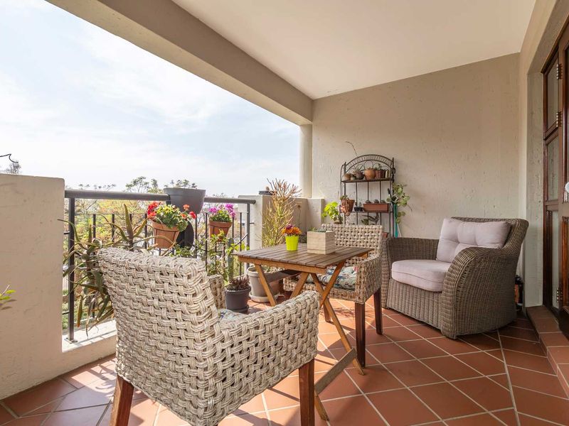 A covered balcony featuring terracotta tiled flooring and a metal balustrade, offering an outdoor space for relaxation.