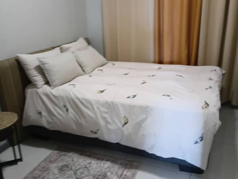 A simple bedroom featuring tiled flooring and neutral curtains, providing a functional and comfortable sleeping space.