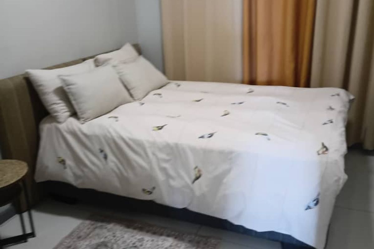 A simple bedroom featuring tiled flooring and neutral curtains, providing a functional and comfortable sleeping space.