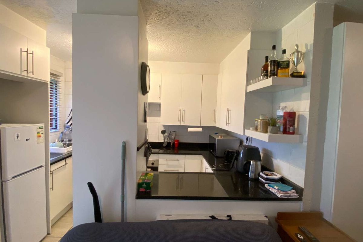 Compact kitchen featuring white cabinetry, contrasting black countertops, and a functional layout with an integrated breakfast bar area.