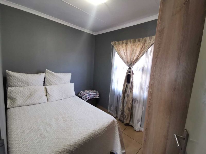 A functional bedroom featuring tiled flooring and a built-in cupboard, finished with neutral grey wall paint.
