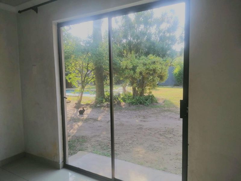 An empty living room featuring a large sliding glass door that provides direct access and views to the rear garden and pool area.