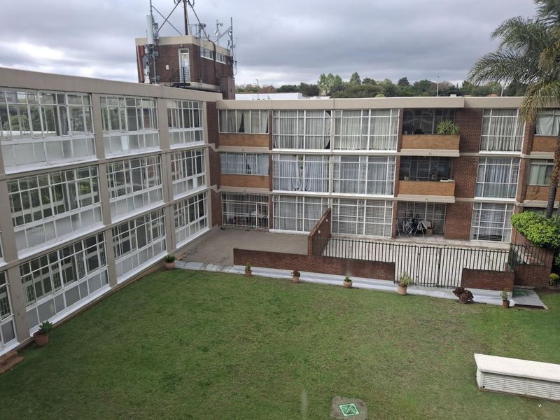 Exterior view of an apartment complex featuring a shared courtyard, brick facade, and large window panels.