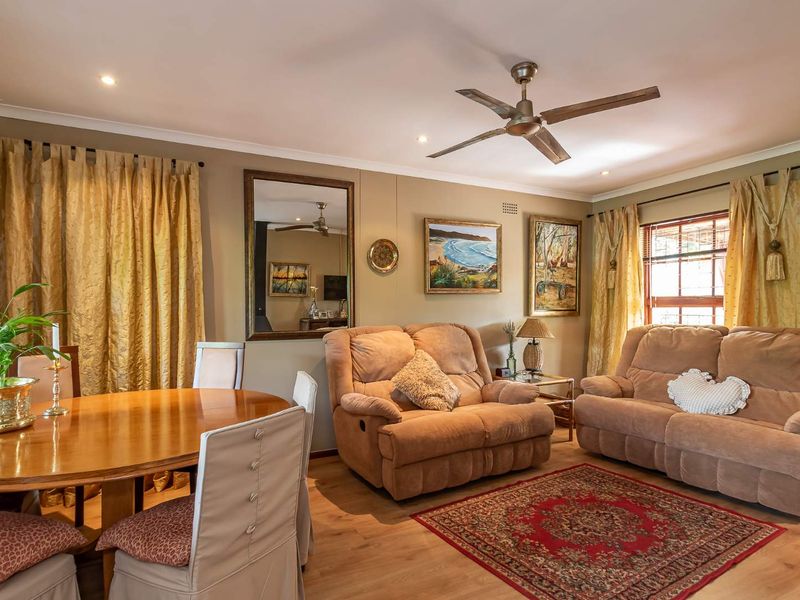 A comfortable living and dining area featuring laminate flooring, a ceiling fan, and recessed lighting, creating a warm and inviting atmosphere.