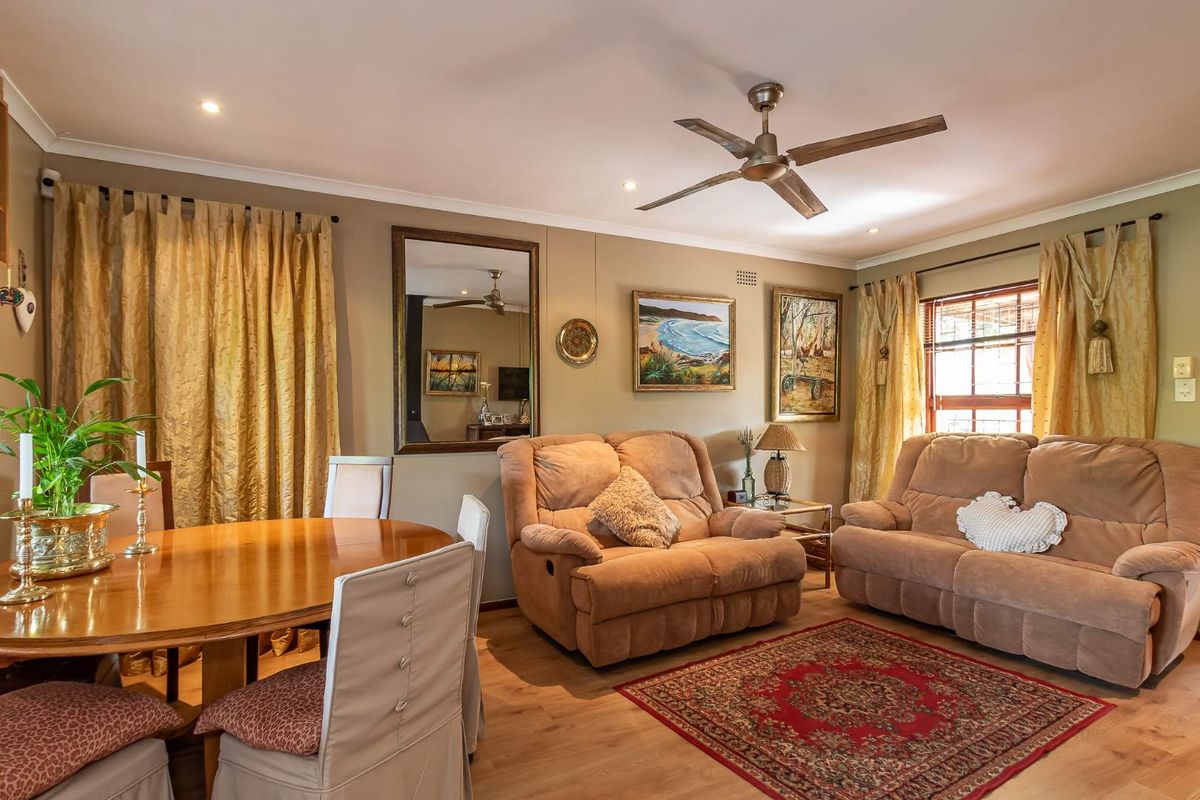 A comfortable living and dining area featuring laminate flooring, a ceiling fan, and recessed lighting, creating a warm and inviting atmosphere.