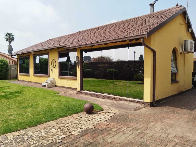 Rear view of the house featuring a tiled roof, brick paved patio area, and large sliding glass doors overlooking the garden.