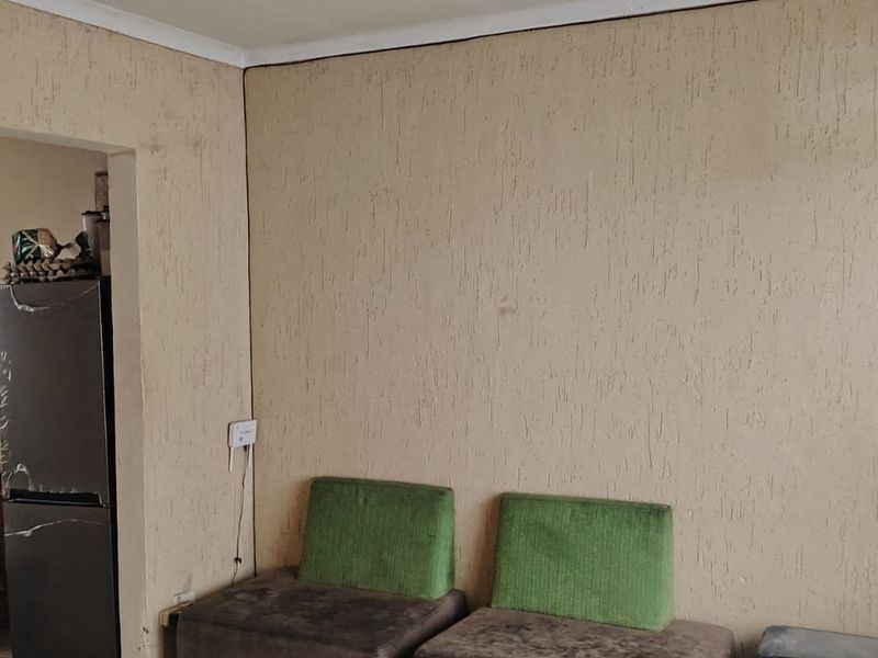 Open plan living area featuring textured wall finishes and coving, requiring cosmetic updates to improve the overall aesthetic and condition of the space.