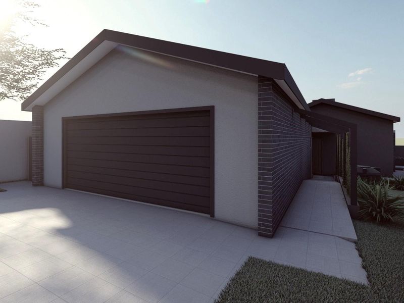 Modern residential exterior featuring a clean brick facade, a large sectional garage door, and a paved driveway with a covered entrance walkway.