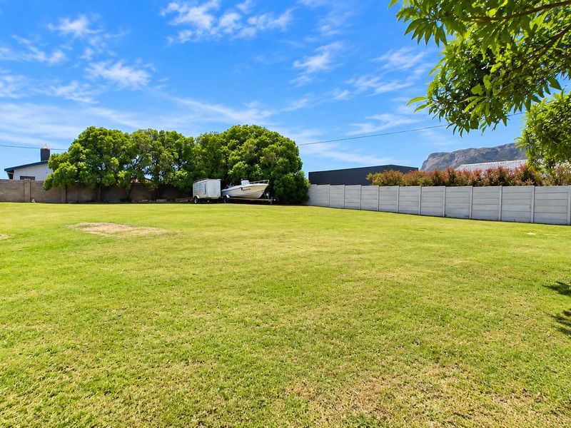 A spacious, well-maintained residential garden featuring a large lawn area enclosed by precast concrete boundary walls.