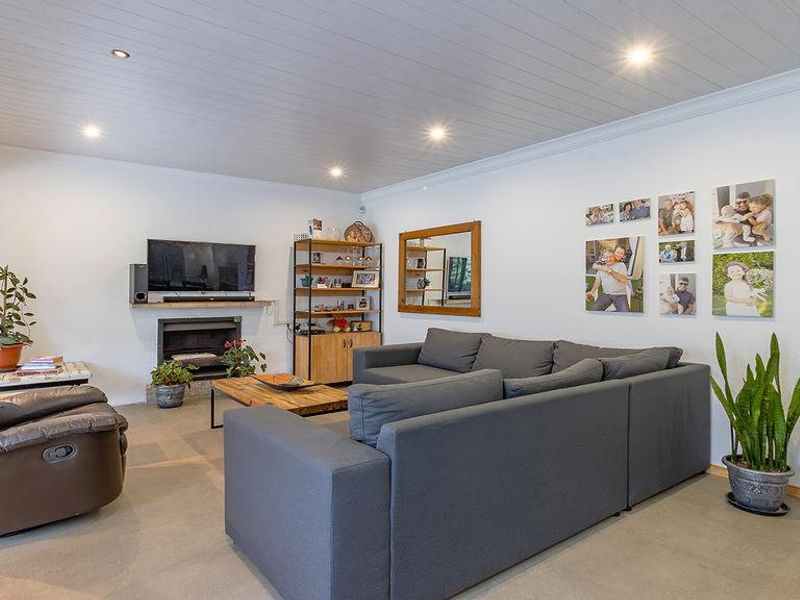 A comfortable living room featuring a built-in fireplace, modern concrete flooring, and a clean tongue and groove ceiling with recessed lighting.